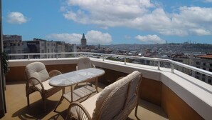 A balcony with wicker furniture and a clear view of a cityscape, including a prominent tower. - Tunel Residence (Istanbul)