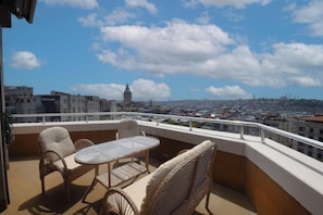 A balcony with wicker furniture and a clear view of a cityscape, including a prominent tower. - Tunel Residence (Istanbul)