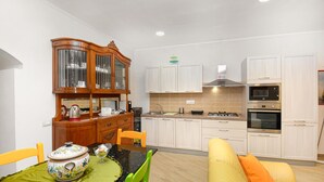 Una cucina moderna con mobili bianchi, forno integrato e zona pranzo con tavolo e sedie.