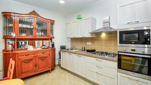 Cucina con piano cottura a gas, forno a microonde, forno e mobile in legno con ante in vetro.