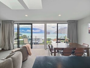 A modern hotel room with a large sliding glass door leading to a balcony with a scenic ocean view. - Quiet Home with Stunning Lake & Mountain Views (Queenstown)