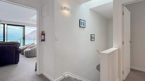 A modern interior with a staircase, a sofa, and a fire extinguisher on the wall. - Quiet Home with Stunning Lake & Mountain Views (Queenstown)