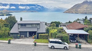 A residential area with a house, a garage, and a car parked in front. - Quiet Home with Stunning Lake & Mountain Views (Queenstown)