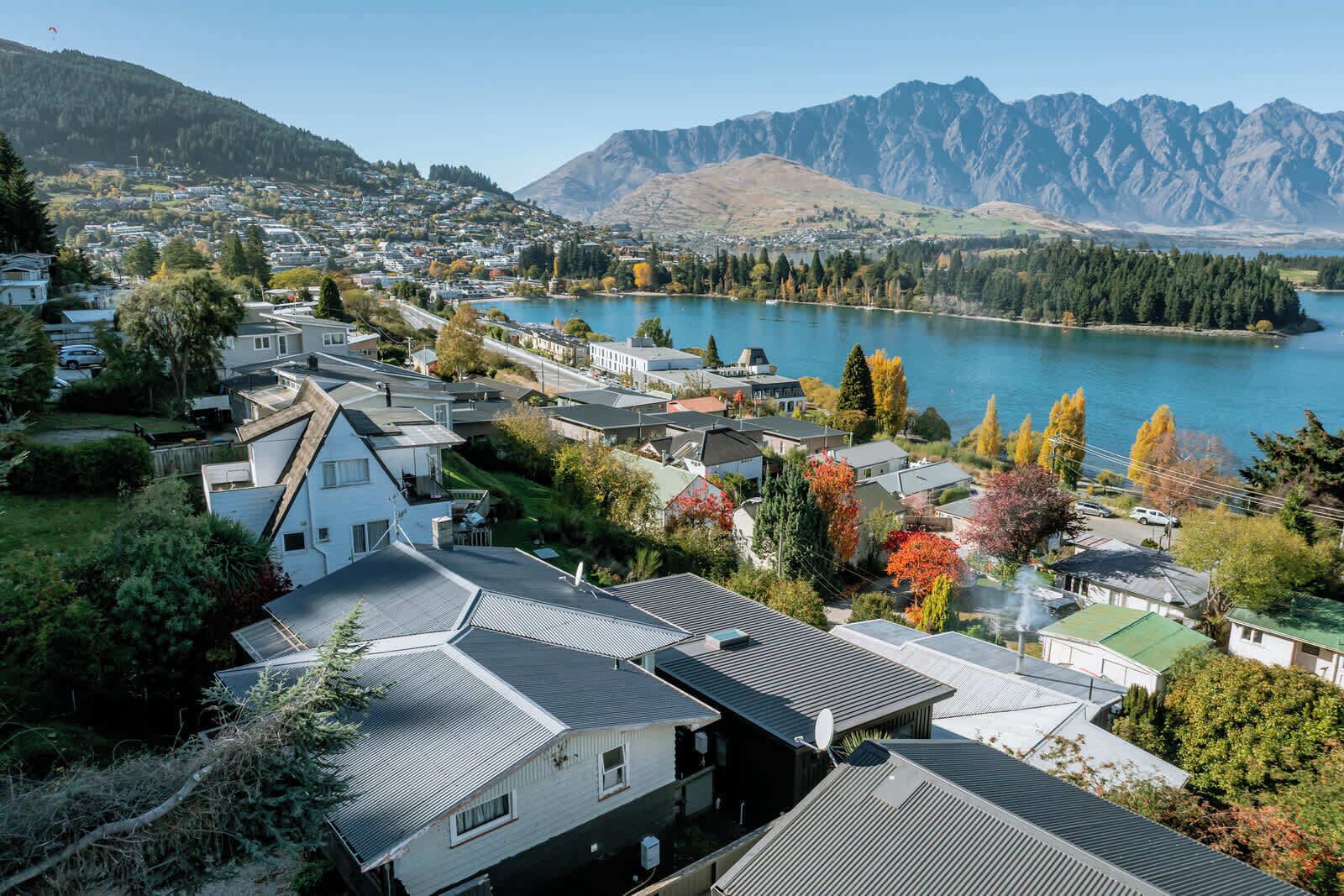 Un barrio residencial con casas, un lago y montañas al fondo.