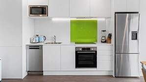 A modern kitchen with white cabinets, a stainless steel refrigerator, a microwave, a dishwasher, and an oven. - Central Charm | 10 Min Walk to CBD (Queenstown)