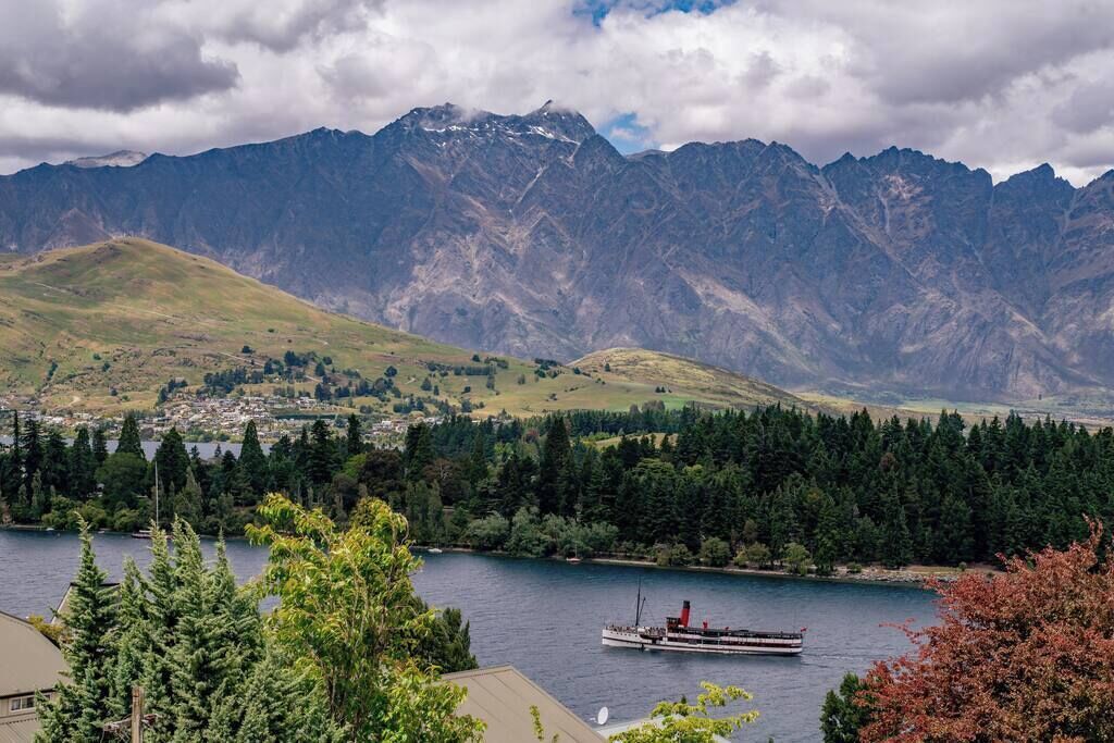 Un lac avec un bateau, entouré de montagnes et d’une ville.
