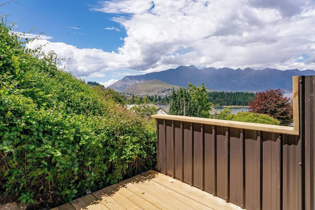 Une terrasse en bois offrant une vue sur les montagnes et un lac.