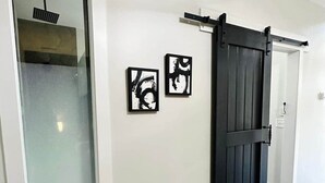 A hallway with a sliding barn door, a large window with a view, and two framed artworks on the wall. - The Kinky Cabin Adult Themed A-Frame (Walker County)