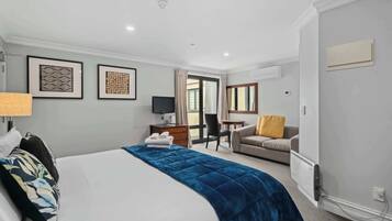 A hotel room with a bed, a desk, a chair, a sofa, and a window.