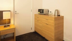 Ein Hotelzimmer mit einem Holztisch, einer Lampe, einer Mikrowelle und einem Wasserkocher.