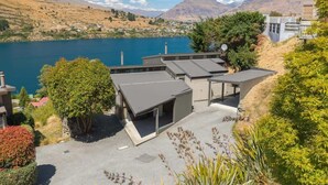 Un edificio moderno con varias habitaciones, un estacionamiento y vistas a un lago y montañas.