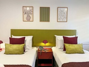 A double room with two beds, a green headboard, and three framed artworks on the wall. - Charming Retreat | Balcony, Views and Garage (Queenstown)