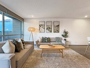 A modern living room with a sofa, a coffee table, and wall art. - Hallenstein Street Retreat, 3Bedroom Queenstown Home (Queenstown)