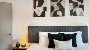 Habitación de hotel con una cama, una mesita de noche con lámpara y arte abstracto en la pared.