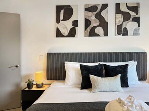 A hotel room with a bed, a nightstand with a lamp, and abstract wall art. - Hallenstein Street Retreat, 3Bedroom Queenstown Home (Queenstown)
