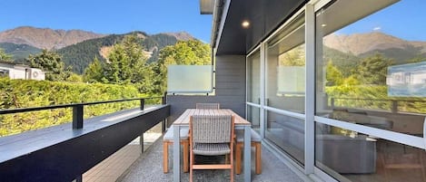 A balcony with a table and chairs, overlooking a mountainous landscape.