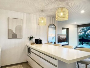A modern kitchen with a central island, pendant lighting, and a large window. - Hallenstein Street Retreat, 3Bedroom Queenstown Home (Queenstown)