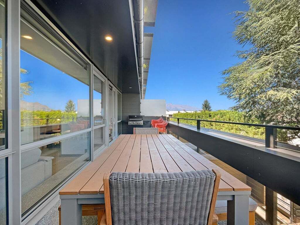 Een balkon met een houten tafel en een rieten stoel, met uitzicht op een prachtig landschap.