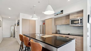 A modern kitchen with a central island, bar stools, and stainless steel appliances. - Sunlit Serenity, Lakefront Apartment (Kawarau Falls)