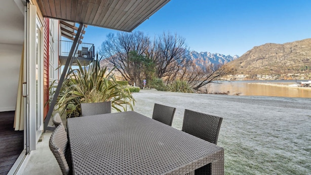 A patio with a table and chairs, a potted plant, and a view of mountains and a lake. - Waterfront 3 Bedroom Marina Gem (Queenstown)