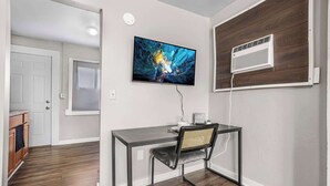 Une chambre moderne équipée d’un bureau, d’une chaise et d’un téléviseur fixé au mur.