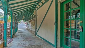 A covered walkway with a green door and windows, leading to a building with a tiled floor and a patterned mat at the entrance. - The Residence on Main (Pioche)
