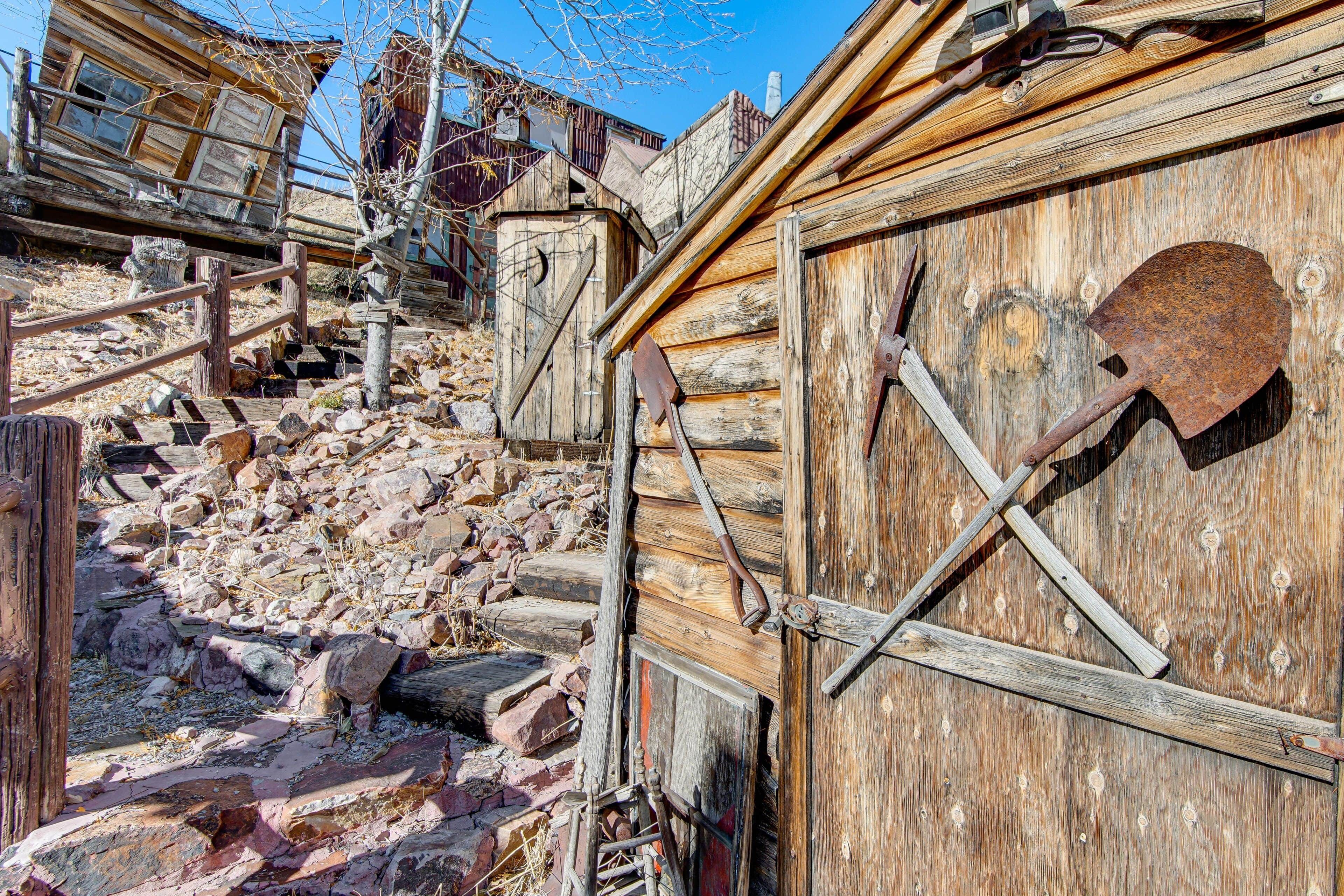 A rustic wooden building with a wooden door and a shovel leaning against it.