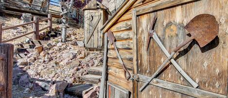 A rustic wooden building with a wooden door and a shovel leaning against it.