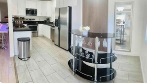 A modern kitchen with white cabinets, stainless steel appliances, and a glass dining table with a metal stand. - "Monthly Stay • Pool - WiFi - Parking - Near Strip (Las Vegas)