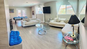 A modern living room with a pool table, two sofas, a glass coffee table, and a blue bean bag. - "Monthly Stay • Pool - WiFi - Parking - Near Strip (Las Vegas)