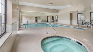 Une piscine intérieure dotée d’un jacuzzi, d’une eau cristalline et d’un sol carrelé.