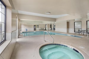 Una piscina interior con jacuzzi, agua cristalina y suelo de baldosas.