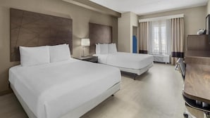 Une chambre d’hôtel avec deux lits, un bureau, une chaise, une armoire et une fenêtre avec des rideaux.