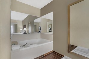 Un bagno moderno con una vasca da bagno ampia, uno specchio e un mobile lavabo con porta asciugamani.
