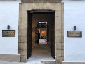 Une entrée ornée d’une arche en pierre et de deux panneaux indiquant « DON JUAN ».