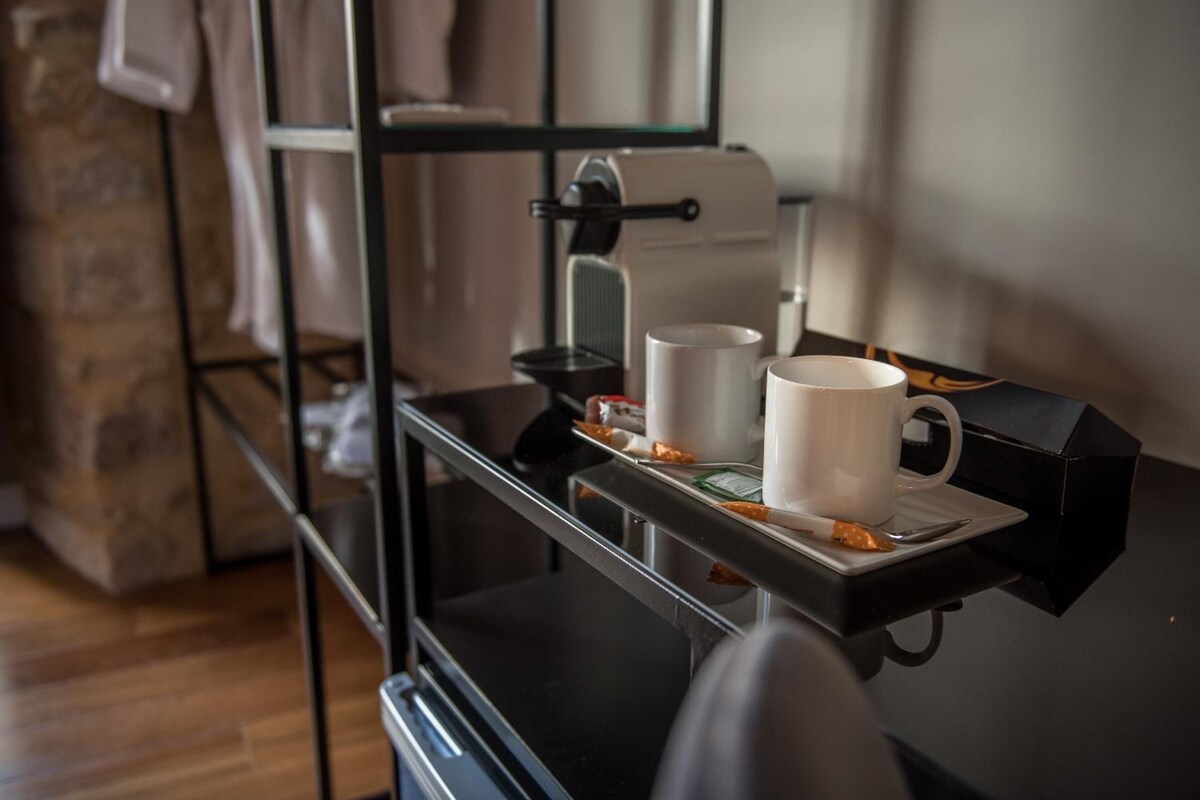 En kaffemaskin med två vita muggar på ett bricka.