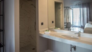 A modern bathroom with a marble shower, a large mirror, and a sink. - Hotelate (Úbeda)