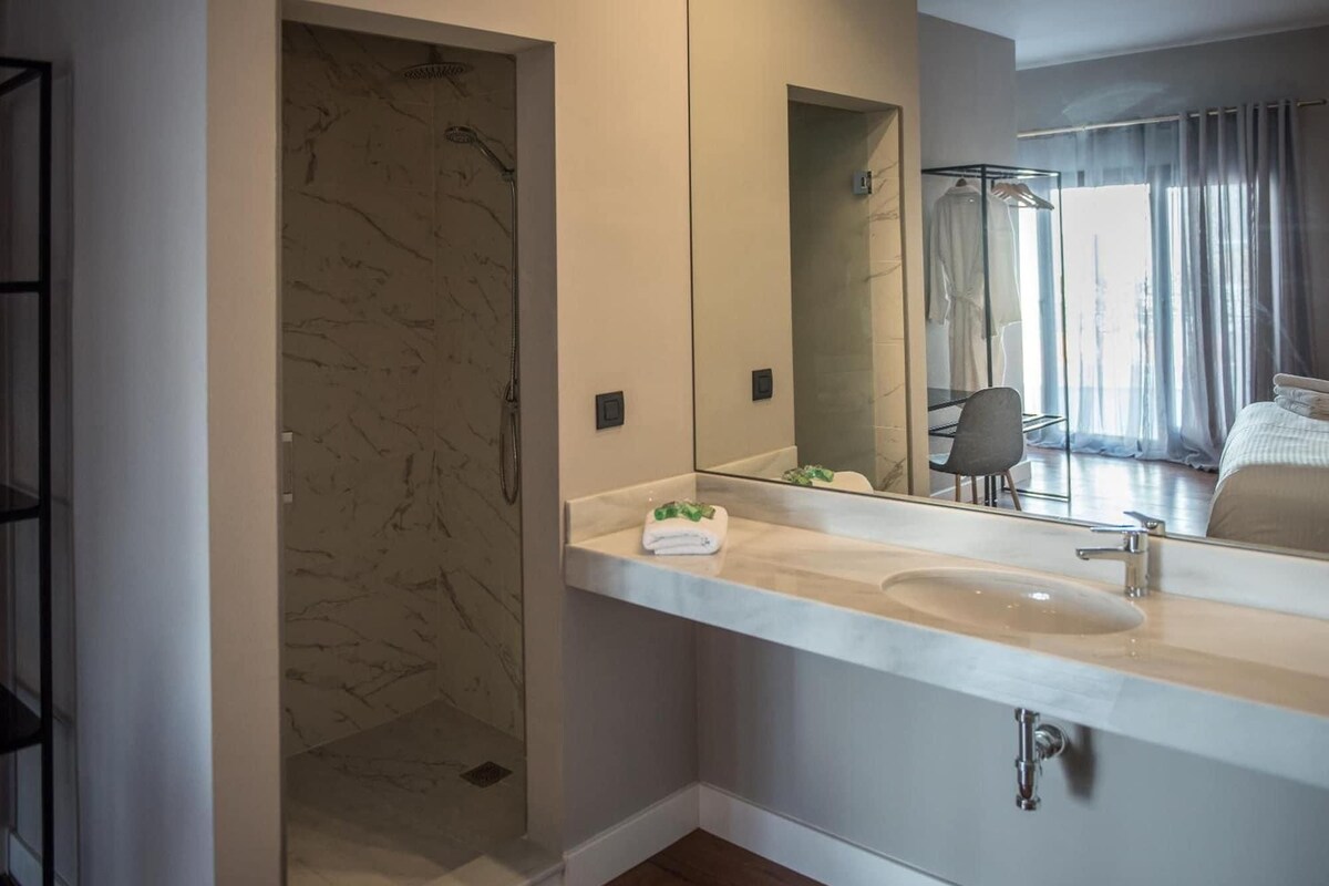 A modern bathroom with a marble shower, a large mirror, and a sink.