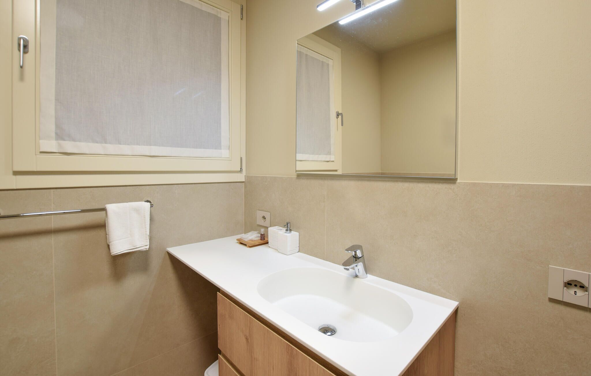 Une salle de bain avec un lavabo blanc, un meuble en bois et un miroir au-dessus.