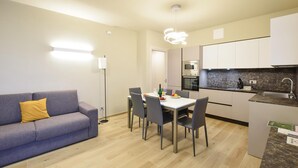 A modern kitchen with white cabinets, a marble countertop, and a built-in oven.