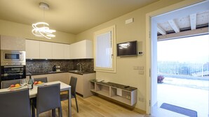 A modern kitchen with a dining area, built-in oven, and a TV mounted on the wall.