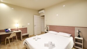 A hotel room with a bed, a desk with a laptop, a chair, a bedside table with a lamp, and an air conditioning unit. - 2 bedroom lovely apartment in Premaor (Premaor)