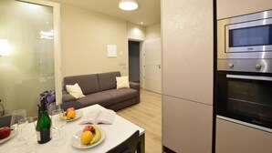 A modern kitchen with a built-in oven, a dining area with a table set for a meal, and a living area with a sofa. - 2 bedroom lovely apartment in Premaor (Premaor)