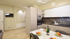 A modern kitchen with a dining table set for two, a microwave, oven, and a coffee maker. - 2 bedroom lovely apartment in Premaor (Premaor)
