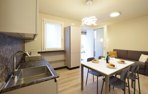 A modern kitchen with a built-in sink, a dining table with chairs, and a sofa in the adjacent living area. - 2 bedroom gorgeous apartment in Premaor (Premaor)