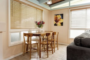 A dining area with a wooden table and chairs, a vase with flowers, and a painting on the wall. - Hale Hibiscus (Hilo)