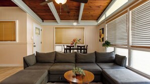A modern living room with a sectional sofa, a wooden coffee table, and a ceiling fan. - Hale Hibiscus (Hilo)