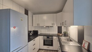 A modern kitchen with white cabinets, a black countertop, a stainless steel sink, and a built-in oven.