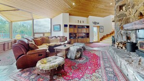 Ein gemütliches Wohnzimmer mit Ledersofa, Hocker und Kamin aus Stein.