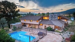Ein zweistöckiges Haus mit Swimmingpool, Terrasse und Blick auf die umliegende Landschaft.